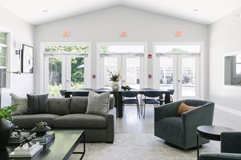 A living room with grey couches, a coffee table, and chairs.